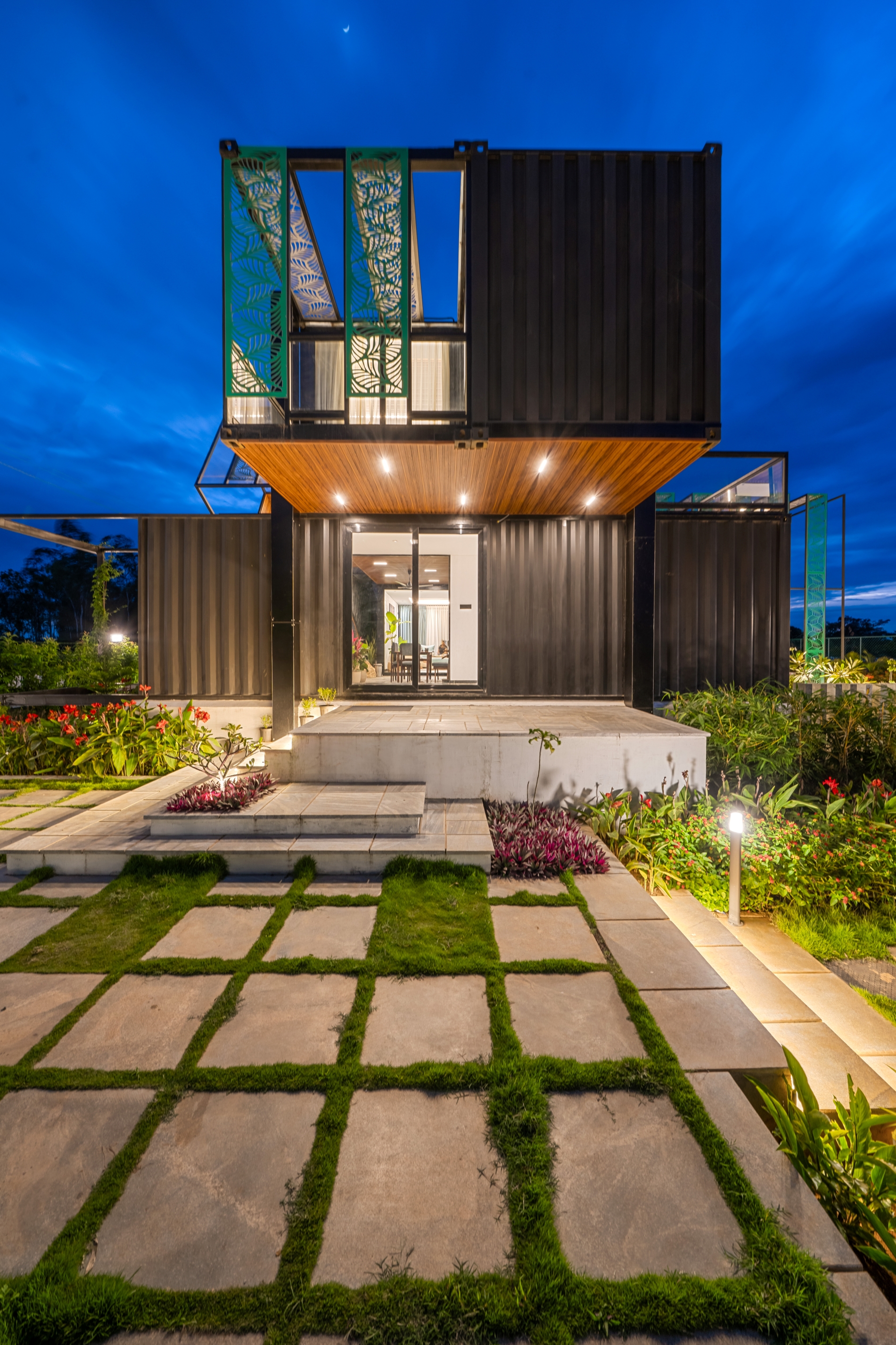 Qbinn Tusker after dusk — container architecture lit against deep blue hour sky